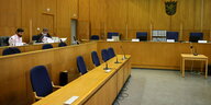 Ein holzverkleideter Gerichtssaal, ganz am Linkenradn sitzen zwei Männer