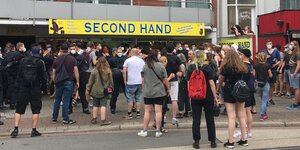 Menschenmenge vor einem breiten Schild mit der Aufschrift "second hand"
