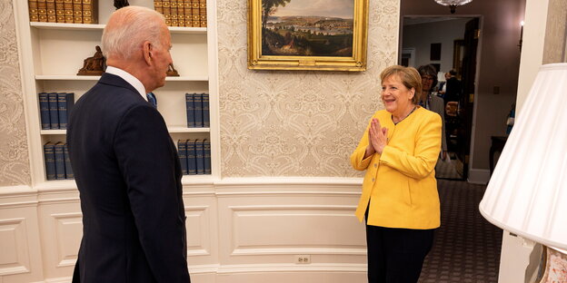 Bundeskanzlerin Angela Merkel im gelben Jackett klatscht freudig und fröhich lachend in die Hände, als US-Präsident Joe Biden , der im Bild von hinten zu sehen ist, sie im Weißen Haus begrüßt