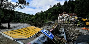 Eine beschädigte Straße und ein Auto nach Überschwemmung in Schuld