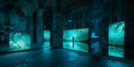 Drei grünlich leuchtende Bildschirme, Blick in die Ausstellung