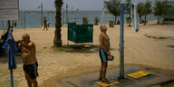 Ein Mann duscht am Strand von Athen