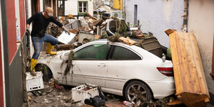 Ein Manns teigt über ein in einer Gasse angeschwemmtes Auto