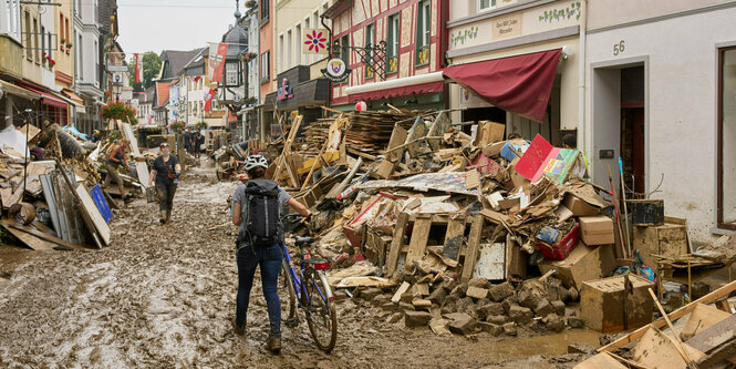 Eine Frau schiebt ihr Fahrrad durch den Schlamm