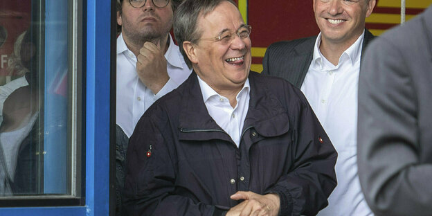 Armin Laschet lacht, in Erfstadt. Der Bundespräsident (nicht im Bild) redet im Vordergrund über die Flutkatastrophe