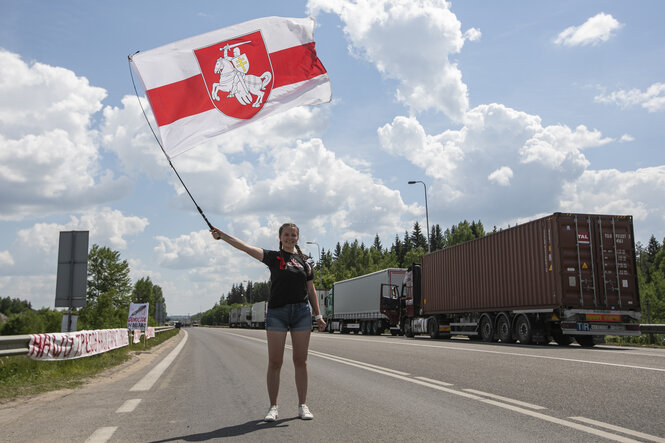 Eine Person schwenkt eine weiß-rote Flagge auf der Straße