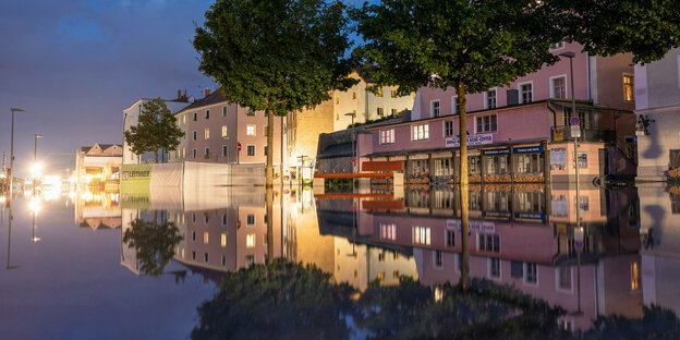 Ufernahe Gebäude spiegeln sich am Abend im Hochwasser