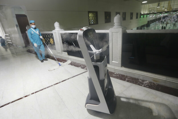 Ein Reinigungsroboter versprüht Desinfektionsmittel in einer Moschee. Ein Reinigungsroboter versprüht Desinfektionsmittel in einer Moschee.