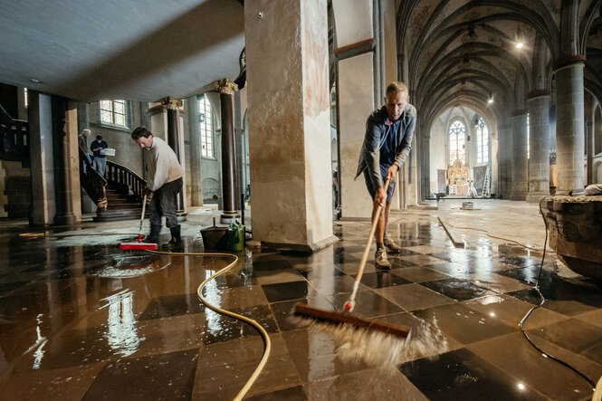 Zwei Personen wischen den Boden in einer Kirche