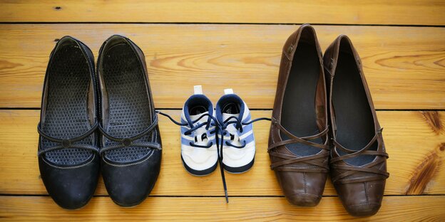 Verschieden Paar Schuhe auf einem Dielenboden.