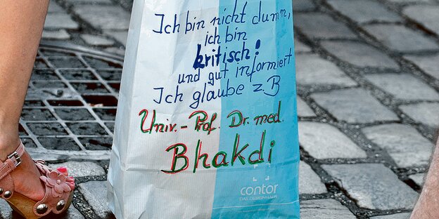 Auf einer Papiertüte steht handgeschrieben der Satz: "Ich glaube Doktor Bhakdi."