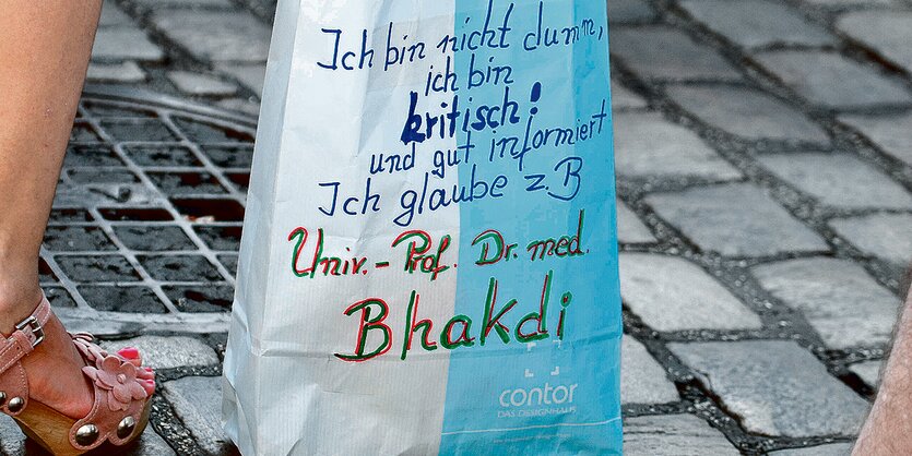 Auf einer Papiertüte steht handgeschrieben der Satz: "Ich glaube Doktor Bhakdi."