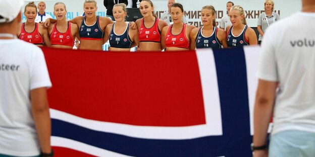 Sportlerinnen vor einer norwegischen Flagge.