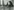 Joseph Beuys eingehüllt in ein riesiges Tuch, er hält einen Stock in der Hand, der Kojote steht auf seinen Hinterbeinen um den Stock genauer in Augenscheint zu nehmen