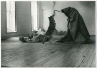 Joseph Beuys eingehüllt in ein riesiges Tuch, er hält einen Stock in der Hand, der Kojote steht auf seinen Hinterbeinen um den Stock genauer in Augenscheint zu nehmen