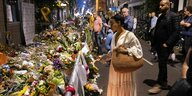 eine Frau steht vor haufenweise Blumen auf einer Straße