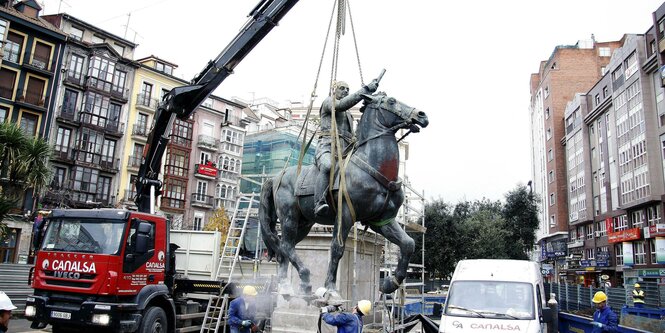 Ein Kran hebt eine Statue von ihrem Sockel.