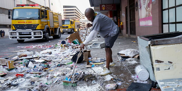 Ein Mann fegt Müll von einer Straße.