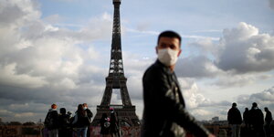 Menschen mit Schutzmasken vor dem Eiffelturm.