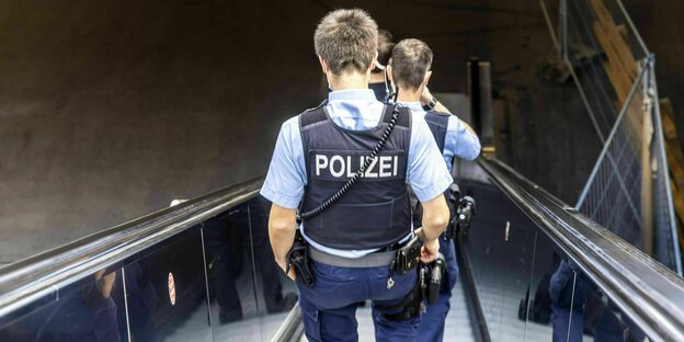 Zwei Polizisten gehen eine Rolltreppe hinab