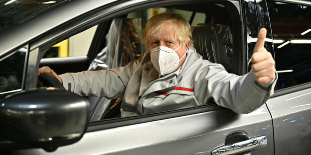 Boris Johnson sitzt in einem Auto und hebt den Daumen.