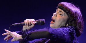 Mireille Mathieu singt mit geschlossenen Augen und leidentshaftlich gestikulierend in ein Mikrofon