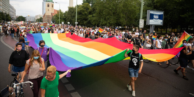 Eine Demo, die von einer Regenbogenfahne angeführt wird: eine Szene vom Dyke* March Berlin im Juli 2020 für lebische Sichtbarkeit