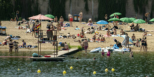 Menschen liegen am Strandbad Plötzensee und sonnen sich