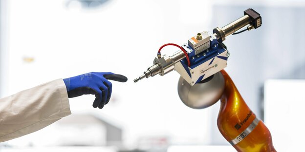 Eine Hand und ein Roboterarm in einem Labor.