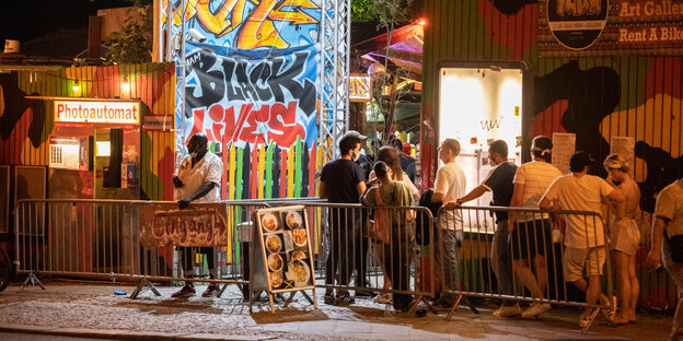 Partygänger warten in den Abendstunden auf Einlass in den Club Yaam in Friedrichshain und stehen artig Schlange