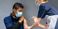 Eine Krankenschwester setzt einer Person eine Spritze.