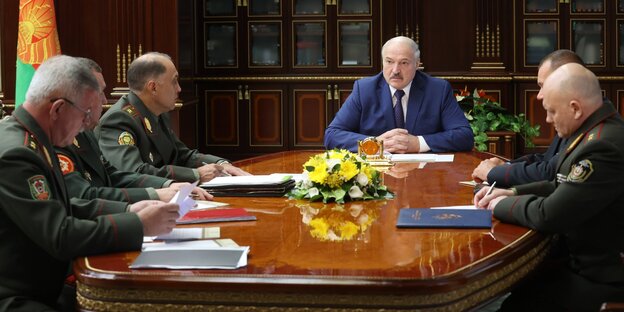 Lukaschenko sitzt mit Militärs am Tisch