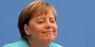 Die Bundeskanzlerin Angela Merkel, leicht von der Seite abgebildet, sitzt vor einer blauen Wand des Bundespressekonferenzraumes. Ihre Augen sind geschlossen. Ihr Gesichtsausdruck wirkt zufrieden, vielleicht etwas selbstgefällig.