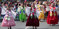 Frauen in traditionellen Kleidern tanzen auf der Straße vor einer Menschenmenge