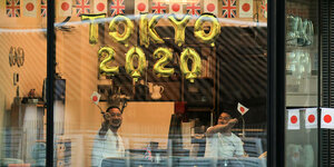 Zwei Olympiafans in Tokio haben ihr Apartement geschmückt und winken mit Winkelementen