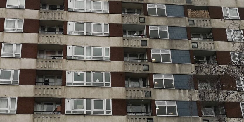 Blick auf ein heruntergekommens Hochhaus mit kleinen Balkons. Die Bandmitglieder von Sault wuchsen auch in Sozialbauten von London auf.