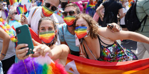 Menschen mit bunten Masken und Pride-Flagge