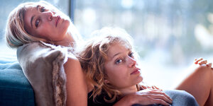Valeria Bruni Tedeschi und Nadia Tereszkiewicz sitzen in einer Filmszene lasziv auf einem Sofa.