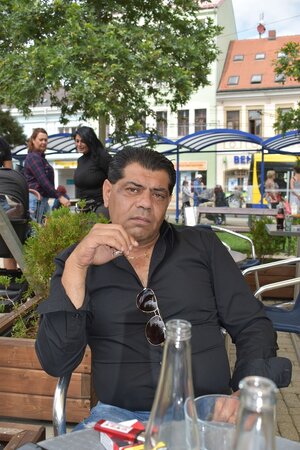 Ein Mann sitzt draußen an einem Tisch. Vor ihm stehen Flaschen Ein Mann sitzt draußen an einem Tisch. Vor ihm stehen Flaschen