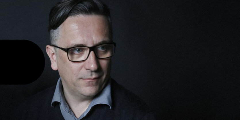 Peter Rehberg mit Brille vor schwarzem Hintergrund.