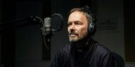 Bernd Hagenkord sitit mit Kopfhöreren vor einem Mikrofon im Studio