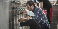 Vater und sein kleiner Sohn bei der rituellen Waschung vor dem Gebet in einer Moschee