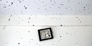 Eine kaputte Uhr und Einschusslöcher in einer Wand