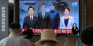 Die Führer Nord- und Südkoreas zwischen NachrichtenstprecherInnen auf einem TV-Bildschirm in einem Bahnhofswarteraum.