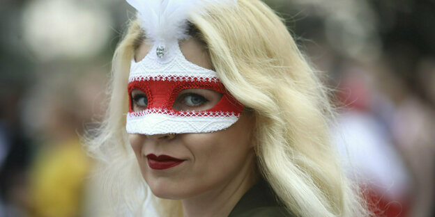Frau mit blonden Haaren und einer Maske rot-weiß