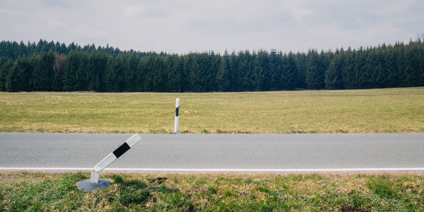 Eine Landstraße mit zwei Pollern. Einer davon ist umgeknickt.