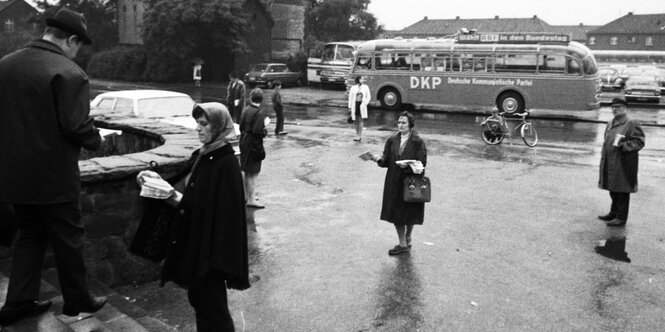 Frauen verteilen Broschüren, im Hintergrund ein Bus mit der Aufschrift DKP