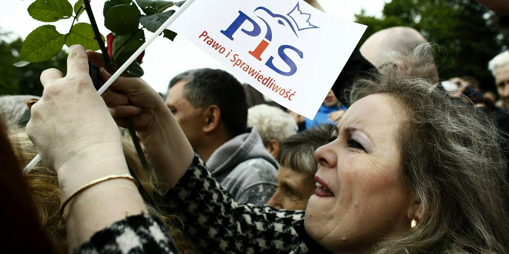 Eine Frau hält eine weiße Fahne mit der Aufschrift PiS