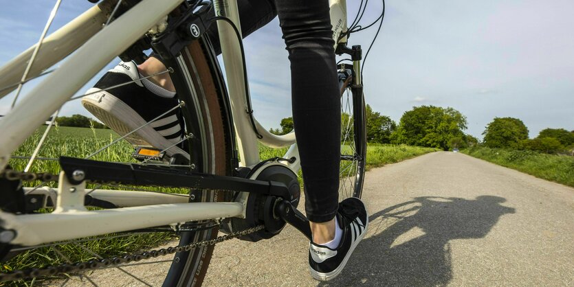 Frau fährt mit einem E-Bike auf einem Fahrradweg im Grünen