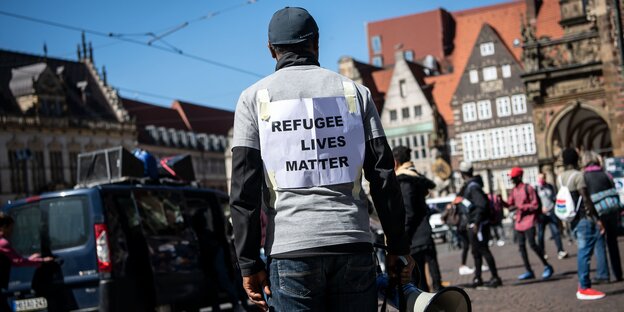Ein Demonstrant steht mit einem Plakat mit der Aufschrift "Refugee lives matter" auf dem Marktplatz.